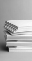 A stack of blank white sheets of paper, angled slightly, resting on a neutral gray background