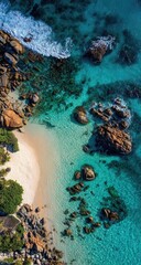 High-angle view of a secluded beach.  Turquoise water laps gently around granite boulders and a pristine white sandy cove. Lush vegetation borders the shoreline