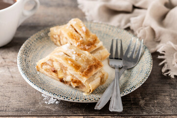 Homemade apple strudel slices in plate on wooden table. Traditional Austrian and German sweet