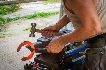 Farrier shaping hot horseshoe with hammer on anvil —rural craftsmanship, blacksmithing, equine care