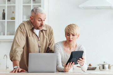 Family economics, bookkeeping, bill payment and taxes. Surprised upset adult wife shows calculator...