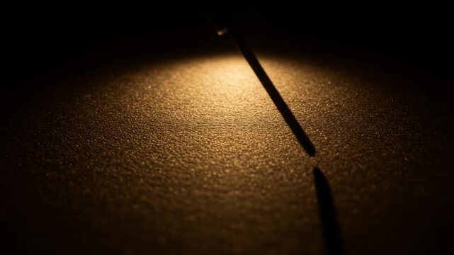 A single thin object casting a long shadow on a textured surface under dim lighting