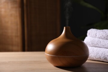 Modern aroma lamp on wooden table indoors, closeup. Space for text