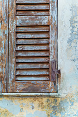 Weathered Wooden Shutter on Antique Stone Wall with Peeling Paint