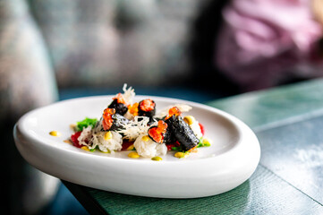 Gourmet seafood dish with rice, seaweed rolls, fish roe, and colorful sauces on a white plate, served in a fine dining setting with artistic presentation