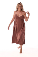 Happy senior woman dancing barefoot wearing brown dress on white background