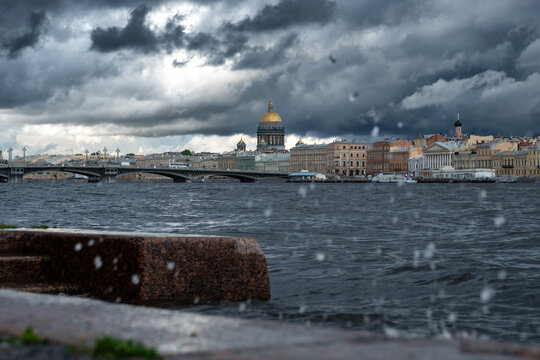 Stormy landscape of Saint Petersburg with splashes of the Neva River and leaden clouds over the city. View from Lieutenant Schmidt Embankment. Russia