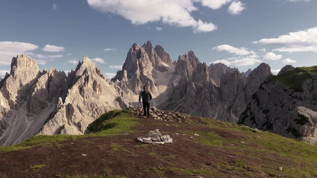 Man running toward cliff edge to pose in front of Cadini di Misurina, Dolomites