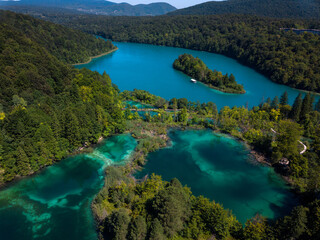 Aerial photography of Plitvice Lakes (Plitvička jezera) in Croatia (Hrvatska). Pedestrians and visitors walking over a wooden bridge between the lakes. Plitvice Lakes National Park.