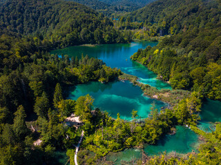 Aerial photography of Plitvice Lakes (Plitvička jezera) in Croatia (Hrvatska). Pedestrians and visitors walking over a wooden bridge between the lakes. Plitvice Lakes National Park.