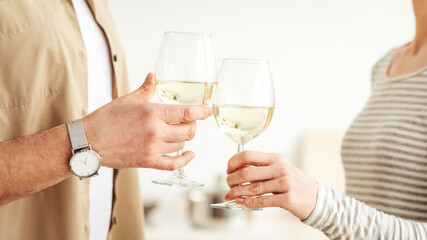 Happy family enjoying romantic time in modern kitchen. Excited adult married couple spending free weekend together at home, husband and wife hold glasses with wine in interior, copy space, cropped