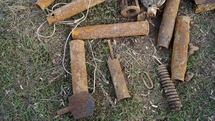 Rusty artillery shells on ground. Old war ammunition remains in soil. Corroded artillery...