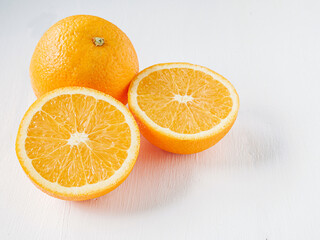 Halved orange fruit on white wooden background, close-up