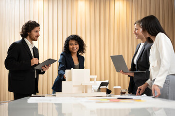 African businesswoman leading a meeting and presenting a housing project plan using a scale model to her colleagues in a modern office