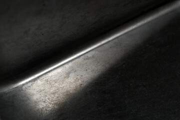 Obraz premium Subtle play of light on a textured metallic surface in shadow