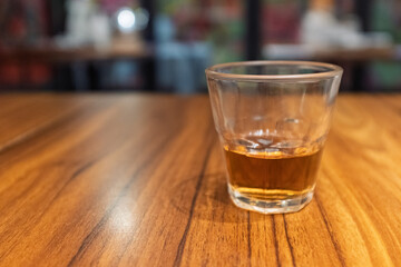A glass of amber drink on a wooden table