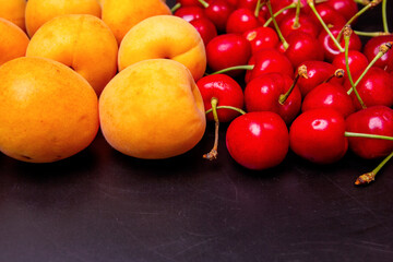 Apricots and cherries on a black background
