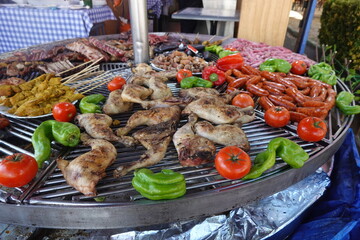 Street food vendor preparing grilled chicken, sausages, and vegetables