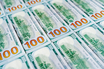 Obraz premium a lot of money banknotes of one hundred 100 American dollars lie on the table evenly laid out, the background is littered with money American green dollars, wealth