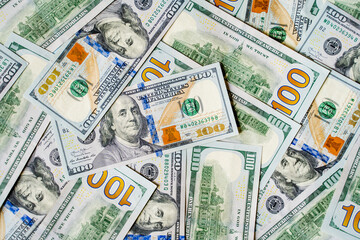 a lot of money banknotes of one hundred 100 American dollars lie on the table in different order, mixed and piled up, the background is piled up with money American green dollars with the image of the