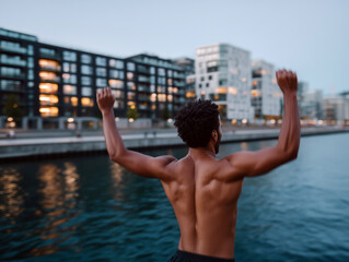 Naklejka premium Young man jumping into river at sunset with joyful expression and cityscape in background
