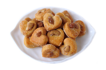 Delicious cashew nut cookies, also known as Singapore cookies, arranged on a white plate. Heart-shaped, golden brown, and sprinkled with sugar, perfect for snacks, desserts, or bakery promotion.