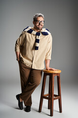 Stylish man in elegant outfit poses confidently in modern studio setting