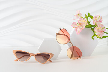 Trendy sunglasses in plastic and metallic frames on white background with flowers. Sunglasses...