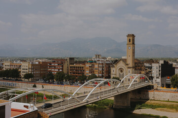 Iconic Tortosa clock tower rising above the city with modern bridge crossing the scenic river below.
