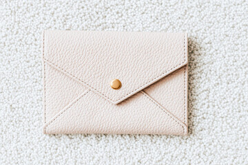 A simple, stylish leather envelope wallet in a soft pink hue, resting on a textured white surface.