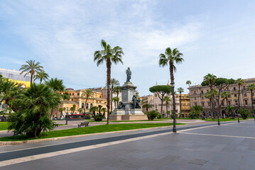 Fototapeta premium Monumental statue in Piazza Cavour square, Rome, Italy, surrounded by palm trees and colorful historic buildings