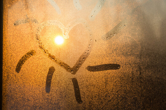 Heart with sunbeams drawn in condesation on a window