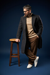 Fototapeta premium Handsome man in glasses showcases stylish elegance in modern studio setting