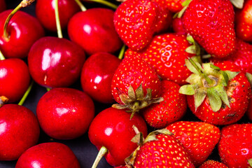 Strawberries and cherries on a black background