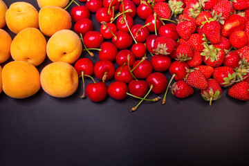 Strawberries, apricots and cherries on a black background