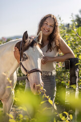 Happy young woman with Paint Horse outdoors in summer