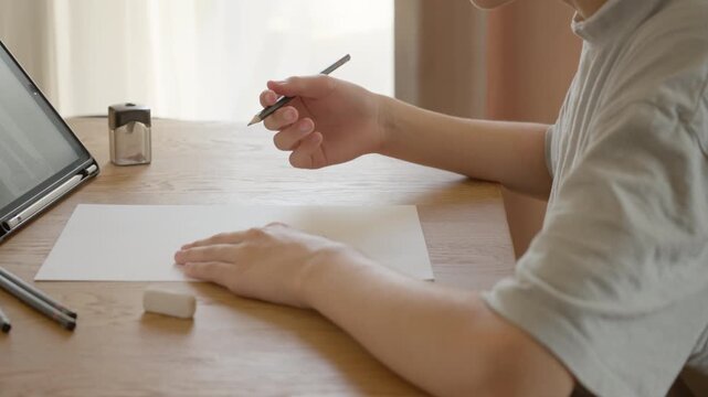 Child's hand correcting a mistake in a drawing with an eraser. The learning process, fixing an error, and continuing to create a sketch. Art lesson, perfectionism, and diligence at home.