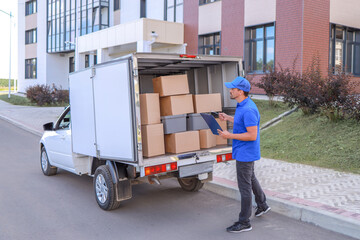 Naklejka premium a courier in a baseball cap loads a van with boxes for delivery. concept merchandising, trade