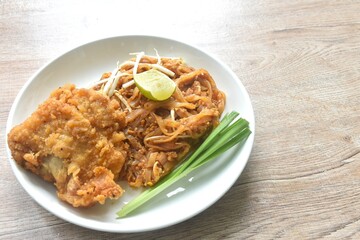 Pad Thai stir fried rice noodles with dry shrimp and egg topping crispy fried chicken on plate 