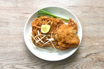 Pad Thai stir fried rice noodles with dry shrimp and egg topping crispy fried chicken on plate 