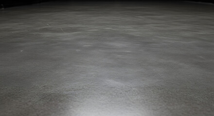 A subtly textured gray surface fills the frame, exhibiting nuanced tonal variations and an abstract quality that conveys a sense of calm, muted depth, and minimalist design aesthetic.