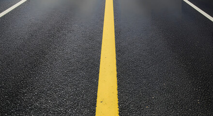 An overhead shot shows freshly paved asphalt with vivid yellow road markings, creating a strong graphic visual, enhanced with the dark, sleek texture and crisp lines, promoting directional themes.