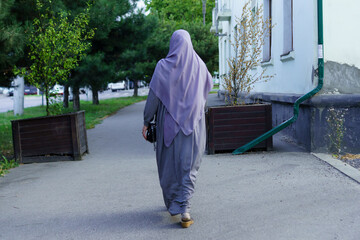 Woman walking on a path surrounded by trees in a calm neighborhood during daytime