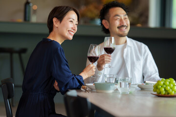 モダンなリビングダイニングで赤ワインを飲む夫婦