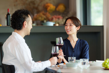 モダンなリビングダイニングで赤ワインを飲む夫婦