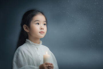 young girl holding candle in her hands stands quietly before window