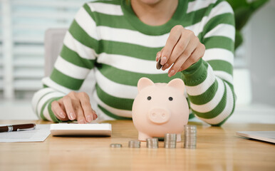 A person calculates finances while saving money, placing coins into a piggy bank. The scene symbolizes budgeting, investment, financial planning, and building future wealth with responsibility and dis