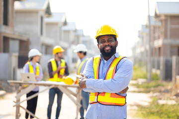 Crossed Arms African American male engineer working : Architect and contractor worker planning and architecture in house building under construction site. Engineering in safety harthat helmet