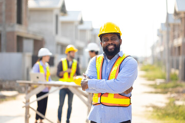Crossed Arms African American male engineer working : Architect and contractor worker planning and architecture in house building under construction site. Engineering in safety harthat helmet