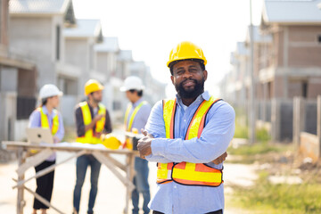 Crossed Arms African American male engineer working : Architect and contractor worker planning and architecture in house building under construction site. Engineering in safety harthat helmet